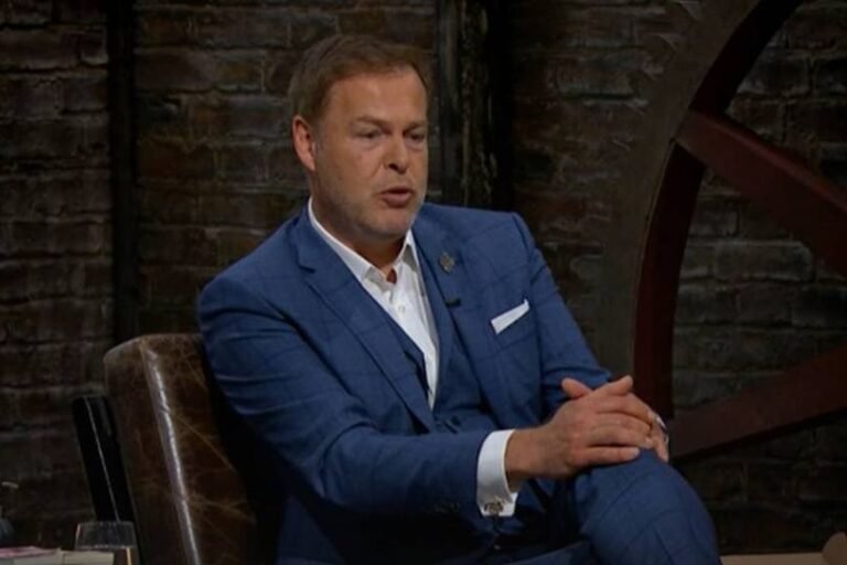 Peter Jones, renowned entrepreneur and Dragons' Den star, standing in front of a high street sports store, with a range of sports equipment and apparel on display, symbolising his latest venture in the UK sports retail market