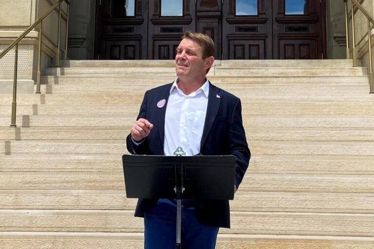A photo of a protest in Wyoming, with people holding signs against the Trump nominee, highlighting the controversy and outrage surrounding the individual's perceived lack of qualifications and behaviour