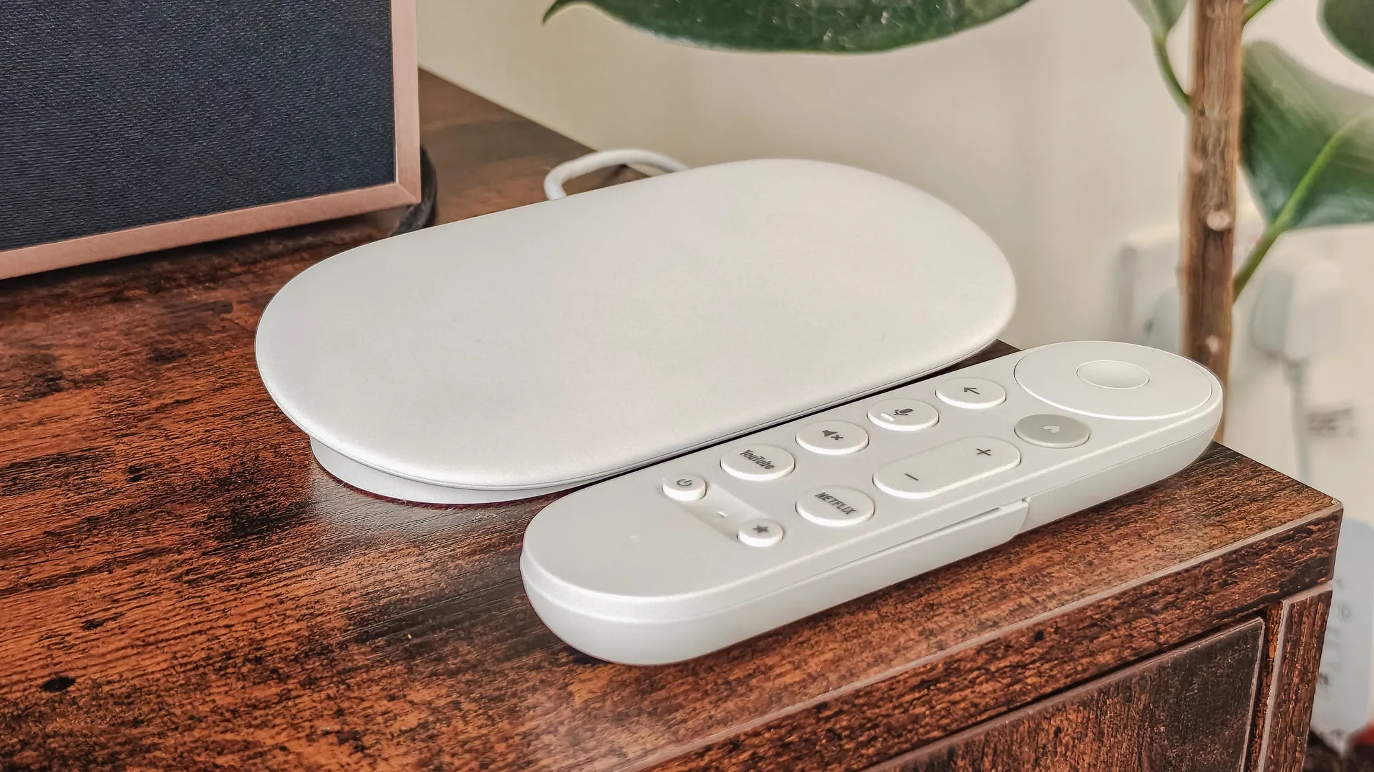 Google TV Streamer device with remote and built-in microphone on a modern living room TV setup