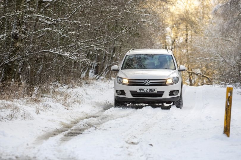 A descriptive image of snow flurries in the UK, with people walking in the snow and cars driving slowly. The image shows the severe weather conditions and the impact of the blizzard on daily life. The primary keyword, UK snow, is naturally included in the alt text.