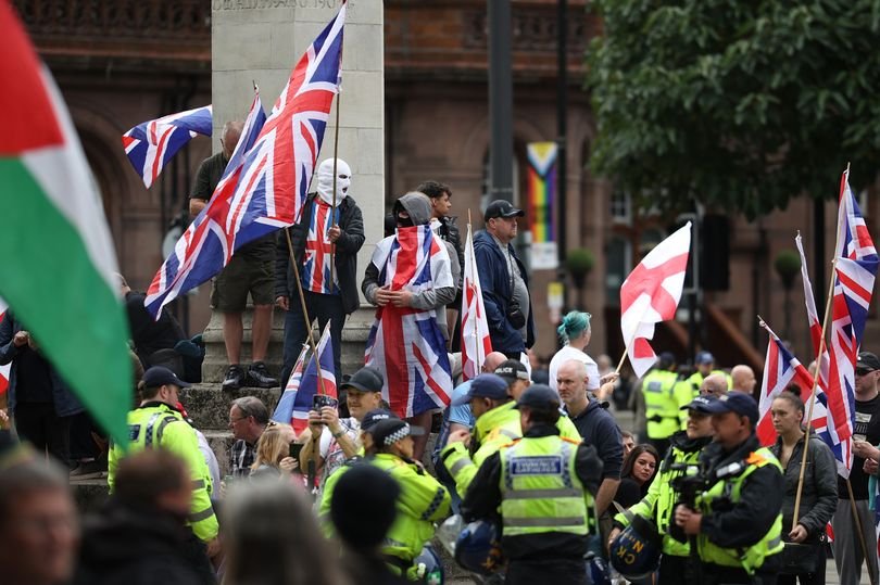 A group of people from different backgrounds and colours standing together, holding signs that read 'Manchester Against Hate' and 'Unity in Diversity', with a clear message that Britain First is not welcome in the city, promoting community unity and social cohesion