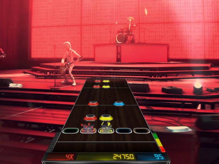Stage Tour game screenshot featuring a band performing on stage with a crowd of fans in the background, showcasing the game's immersive music experience and community engagement features, with the classic five-fret note highway and customizable band members
