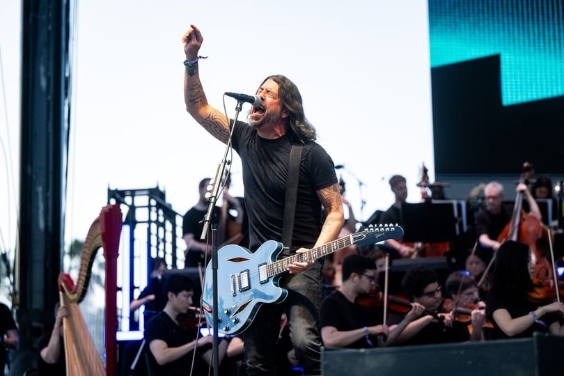 Foo Fighters performing live on stage with a massive crowd and colourful lighting, the primary keyword is Foo Fighters