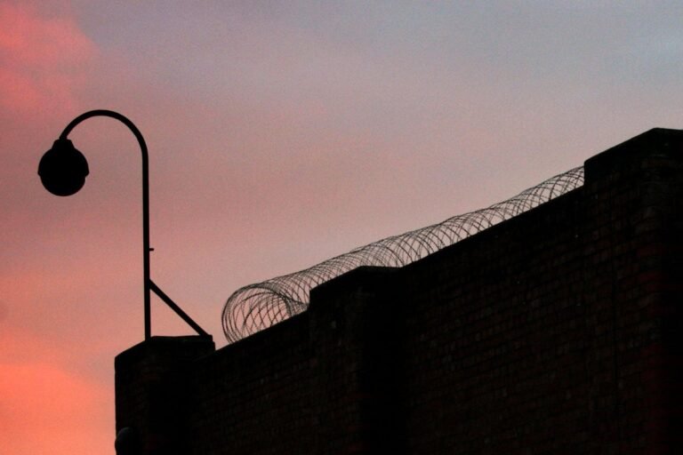 A suspected rapist has left the country after being accidentally set free, sparking widespread outrage and concern among the public and law enforcement agencies, with a photo of a person in handcuffs in the background, representing the accidental release of a suspected rapist