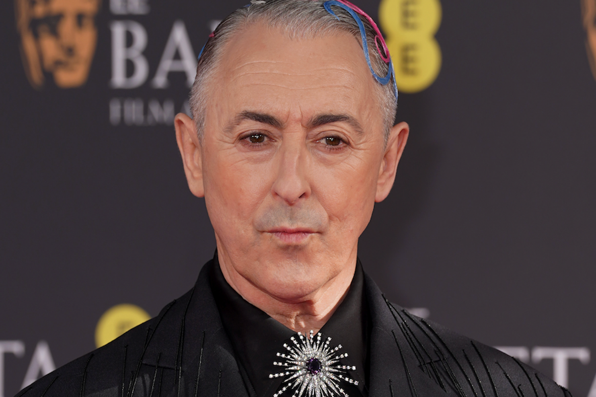 Alan Cumming looking disappointed and critical, with a BBC logo in the background, highlighting the controversy surrounding the racial slur incident