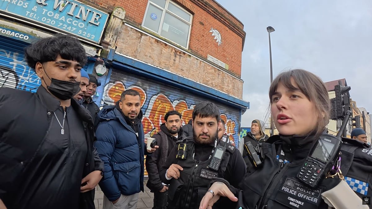 A Met Police officer stands firm while defending a Christian preacher's right to free speech in Whitechapel, as a crowd of onlookers gathers to watch the scene unfold, with some voicing their discontent, in this poignant display of commitment to free speech and community sensitivities, with the preacher's message being heard loud and clear, as the officer works to maintain public order, in a situation that underscores the need for empathy and understanding in such delicate situations, with the UK's free speech laws being put to the test, in a case that will have significant implications for the future of free speech in the UK, and the role of law enforcement in safeguarding individual freedoms