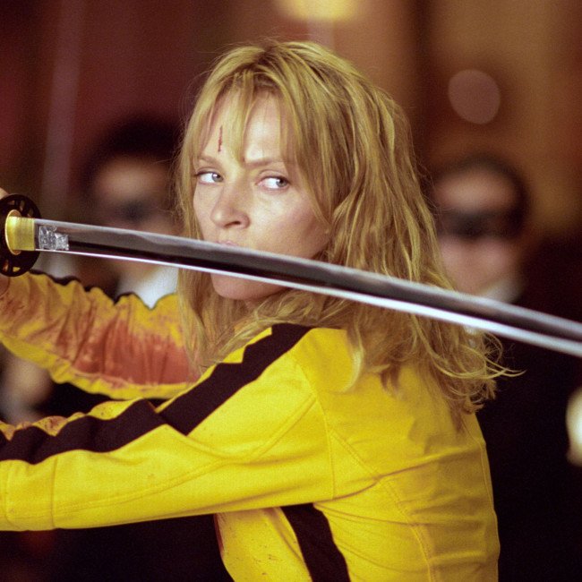 A descriptive image of The Bride from Kill Bill, with her iconic yellow jumpsuit and sword, highlighting the primary keyword cinema heroes in a natural and descriptive way, with a focus on the colour and intensity of the scene