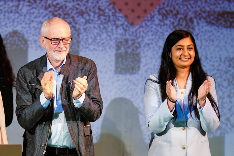 Jeremy Corbyn speaking at a party conference, surrounded by supporters, with a focus on his new role as parliamentary leader