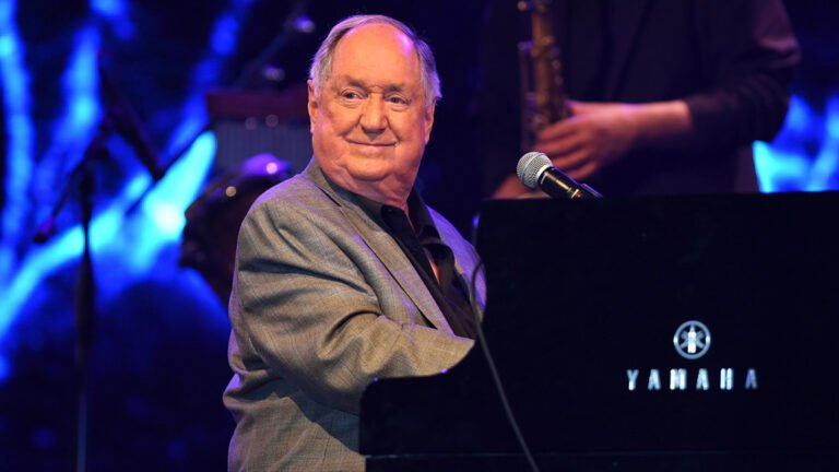Neil Sedaka, a music legend with a career spanning over six decades, performing on stage with his iconic piano, leaving a lasting impact on the music industry with his unique voice and style