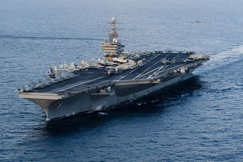 The USS Abraham Lincoln aircraft carrier is seen in the Persian Gulf, with a ballistic missile flying in the background, as tensions between the US and Iran escalate, with the primary keyword being USS Abraham Lincoln