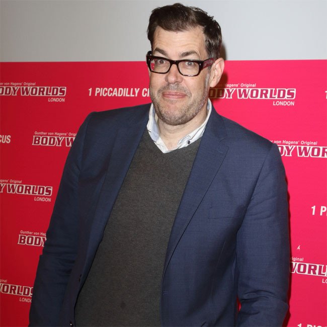 Richard Osman, a charismatic television presenter, posing with a confident smile, showcasing his unique sense of style and colour, against a vibrant background, highlighting his personality and charm