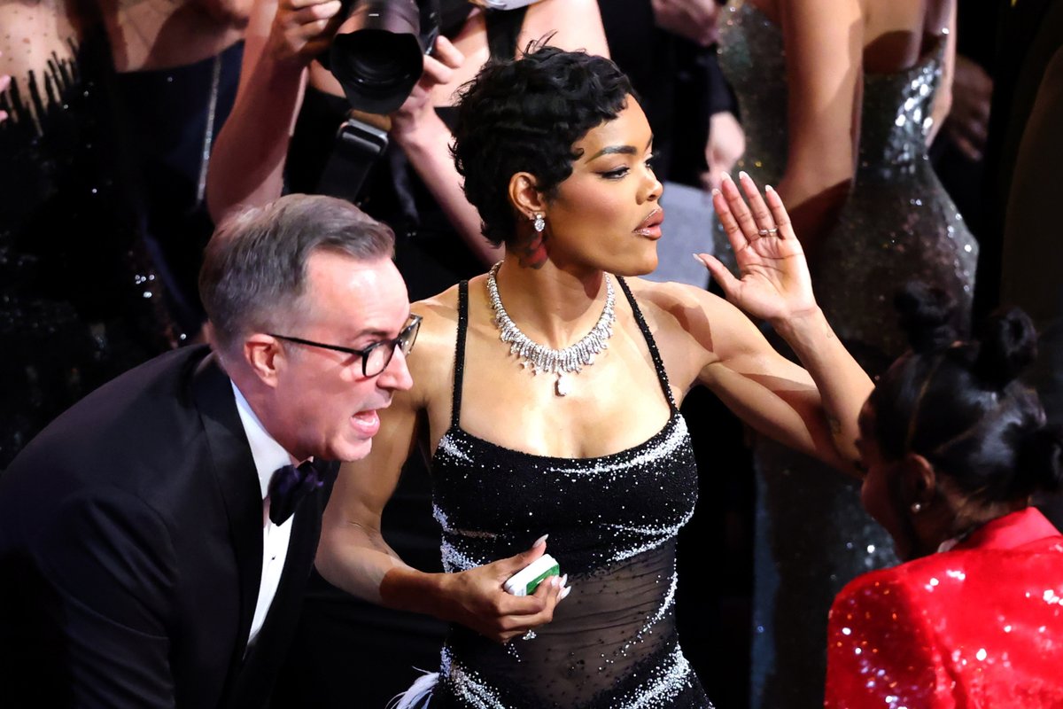 Teyana Taylor posing on the red carpet at the Oscars, with a shocked expression on her face, amidst a crowd of people, representing the chaos and controversy surrounding the backstage altercation, with a focus on celebrity news and entertainment