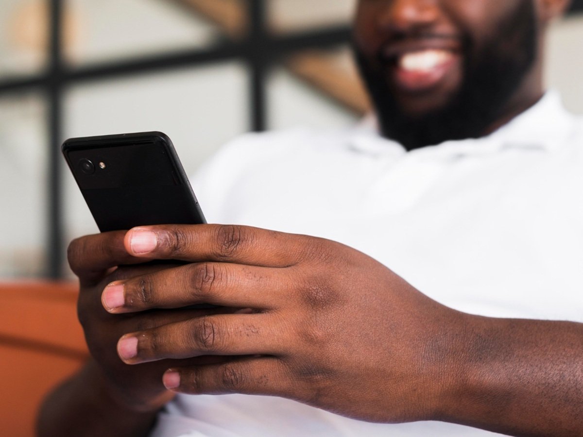 A person holding a 4G smartphone, with a cityscape in the background, highlighting the importance of affordable 4G devices in the UK, with a focus on the GSMA's initiative to increase access to 4G technology