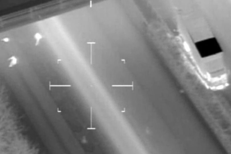 A police car and helicopter on the M6 motorway during a high-speed chase, with a dog unit in the background, highlighting the dramatic nature of the pursuit on the UK's motorways