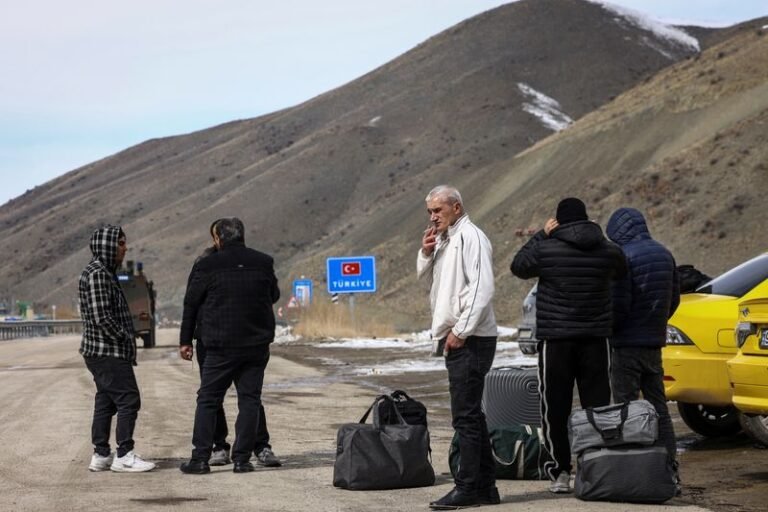 A group of migrants trudging through the snow-covered mountains, their faces filled with determination and desperation, as they attempt to cross the Iran-Turkey border, a journey fraught with risks and uncertainties, with the primary keyword being migrant crisis