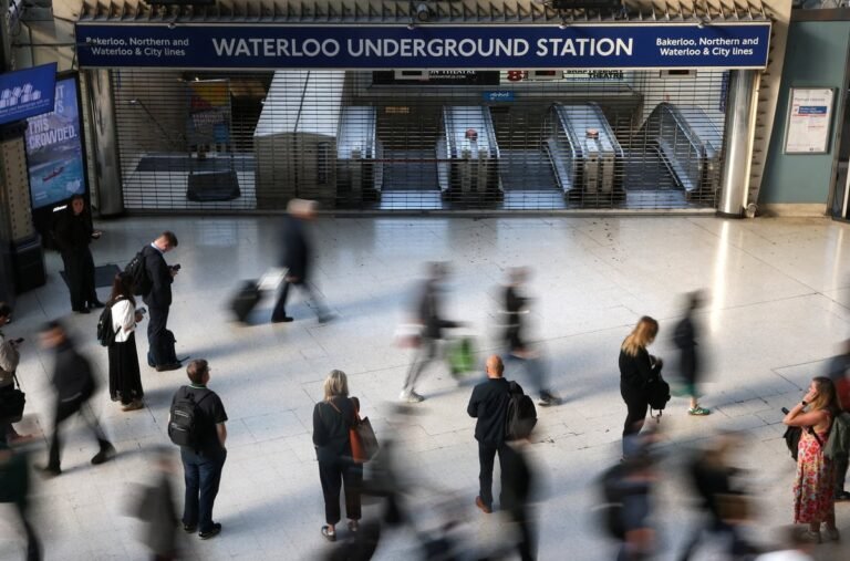 A crowded London Underground platform with a sign reading 'Tube Strike' in the foreground, highlighting the commuter disruption caused by the RMT Union's industrial action, with the primary keyword phrase 'London Tube Strikes' included naturally