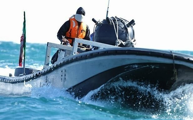 A US Navy ship navigates through the Hormuz Strait, with Iranian minelayers in the background, highlighting the importance of maritime security in the region and the need to protect international shipping lanes from the threat posed by these devices