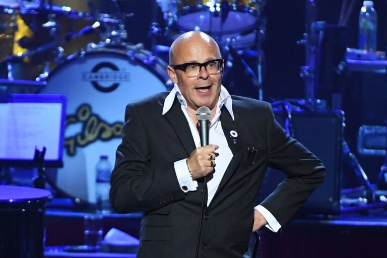 Harry Hill, a British comedian, sitting on a couch with a concerned expression, highlighting his struggles with anxiety and paranoia, a serious mental health issue that affects many people