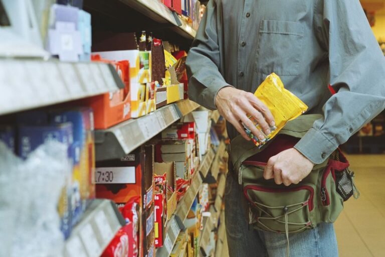 A photo of a person shoplifting in a store, with a blurred face and a security camera in the background, highlighting the need for effective security measures to combat the rising tide of shoplifting in the Midlands