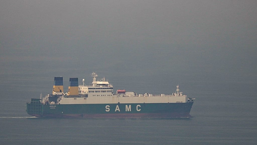 Iran's military personnel standing guard near the Strait of Hormuz, with a US warship in the background, as tensions rise between the two countries over the critical waterway, a vital route for international oil shipments
