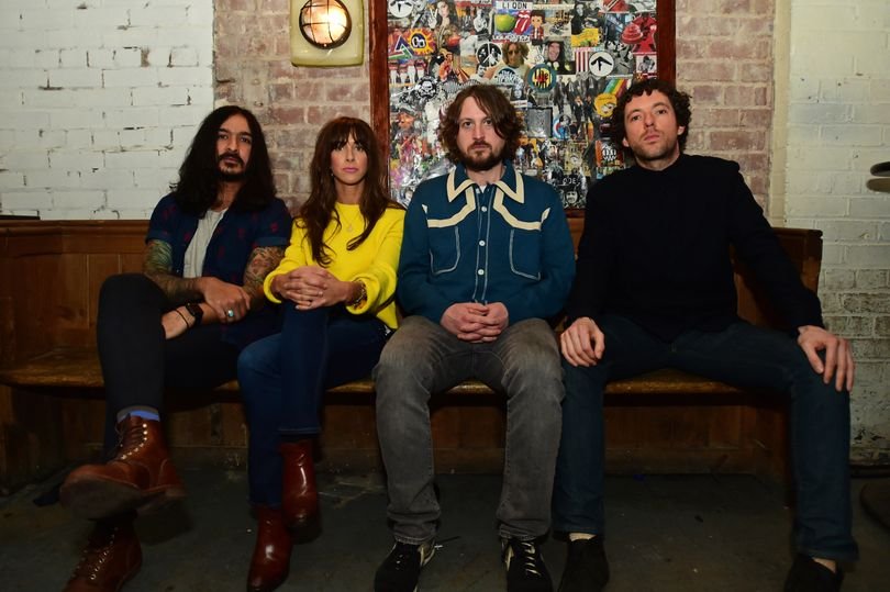 A photo of The Zutons performing live, with a crowd of fans in the background, highlighting the band's energetic and colourful stage presence, with a focus on the primary keyword 'hate crime'
