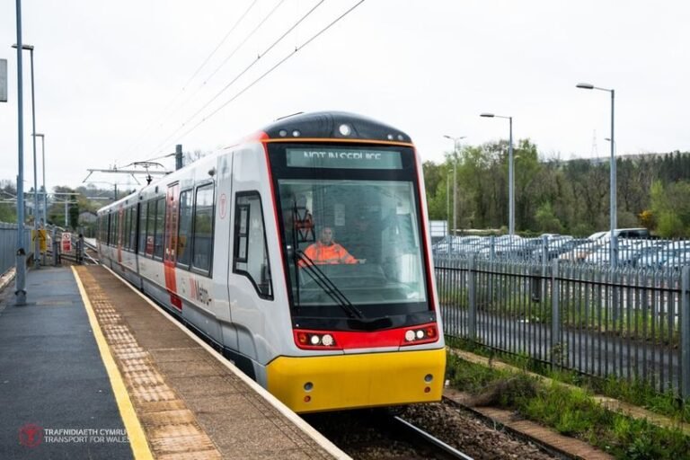 A new train heading for Wales, with a scenic landscape in the background, showcasing the completion of the landmark electrification project, which is expected to improve the railway network and reduce carbon emissions, with a focus on sustainable transport