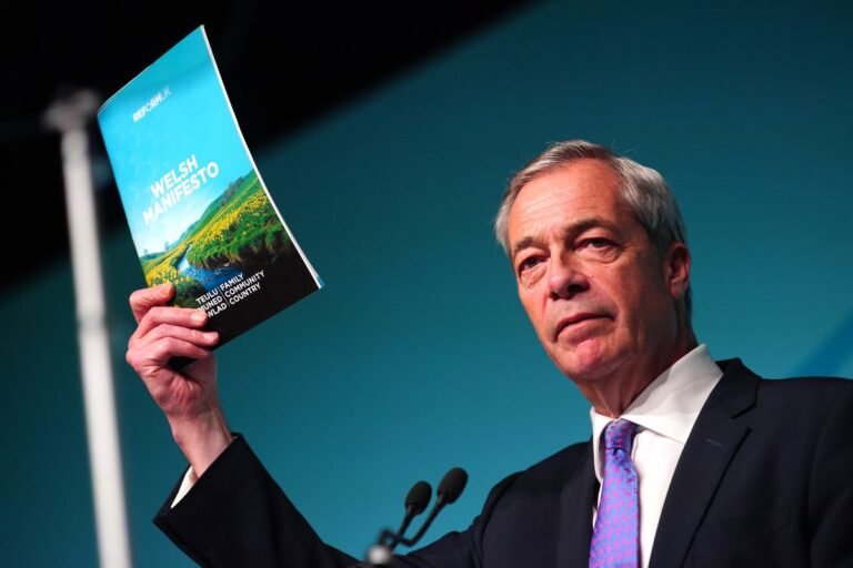 Reform candidates in Wales posing for a photo with a mix of serious and smiling faces, surrounded by Welsh flags and banners with their party colour and logo, ahead of the Senedd election