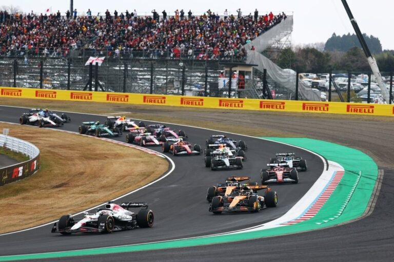 Formula 1 cars racing at the Japanese Grand Prix, with a crowd of fans in the background, watching the F1 live streams