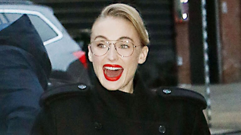 Sophie Turner as Lara Croft, standing in front of a ancient temple with a bow and arrow, with a concerned expression on her face, as the filming of the reboot has been delayed due to her back injury, with the crew and cast waiting for her recovery