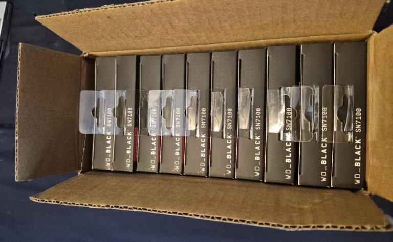 A photo of 10 WD Black SN7100 NVME SSDs, with a surprised user in the background, highlighting the unexpected gift of free hardware in the UK