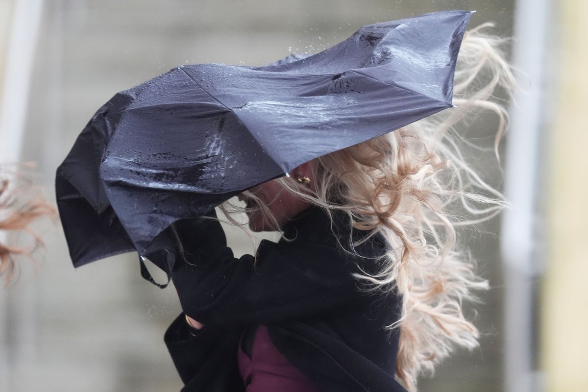 A photo of a rainy street in the UK, with people holding umbrellas and walking in the rain, as the Easter bank holiday weekend weather forecast predicts unsettled conditions