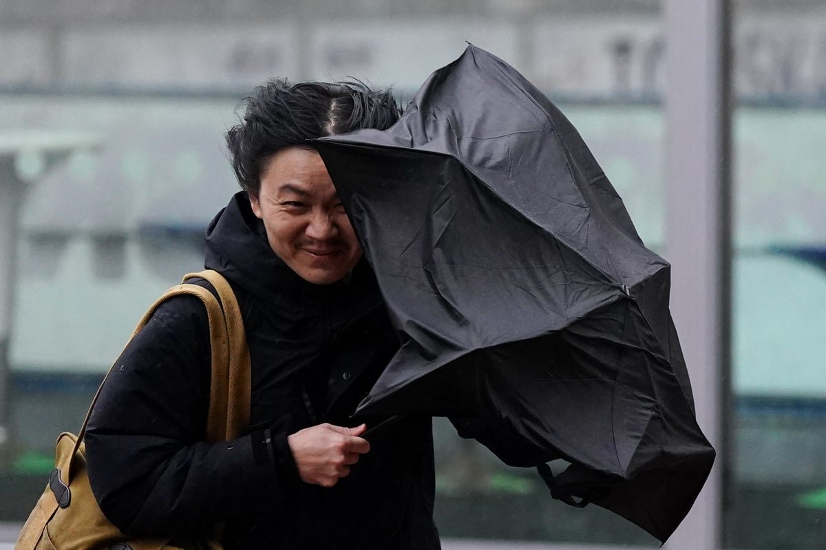 A photo of a rainy street in the UK with a yellow warning sign, symbolising the Easter bank holiday weather forecast with strong winds and heavy rainfall, affecting various regions across the country