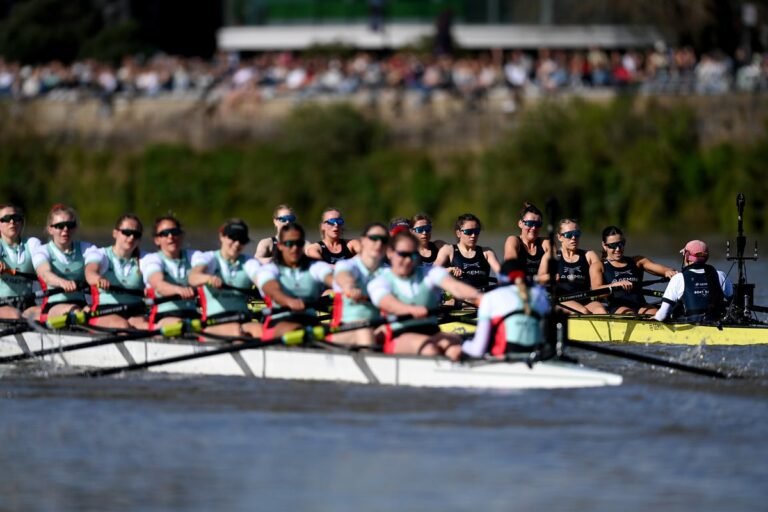 The Oxford and Cambridge boats racing along the River Thames, with spectators cheering them on from the riverbank, showcasing the excitement and colour of this prestigious sporting event, with the primary keyword being Boat Race