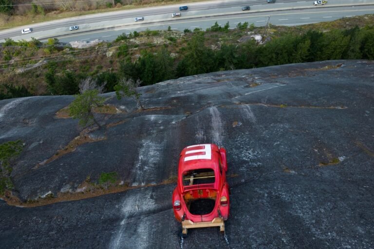A car suspended on a rock face, with authorities warning the public to stay away due to safety concerns and potential environmental damage, highlighting the importance of responsible behaviour and environmental conservation
