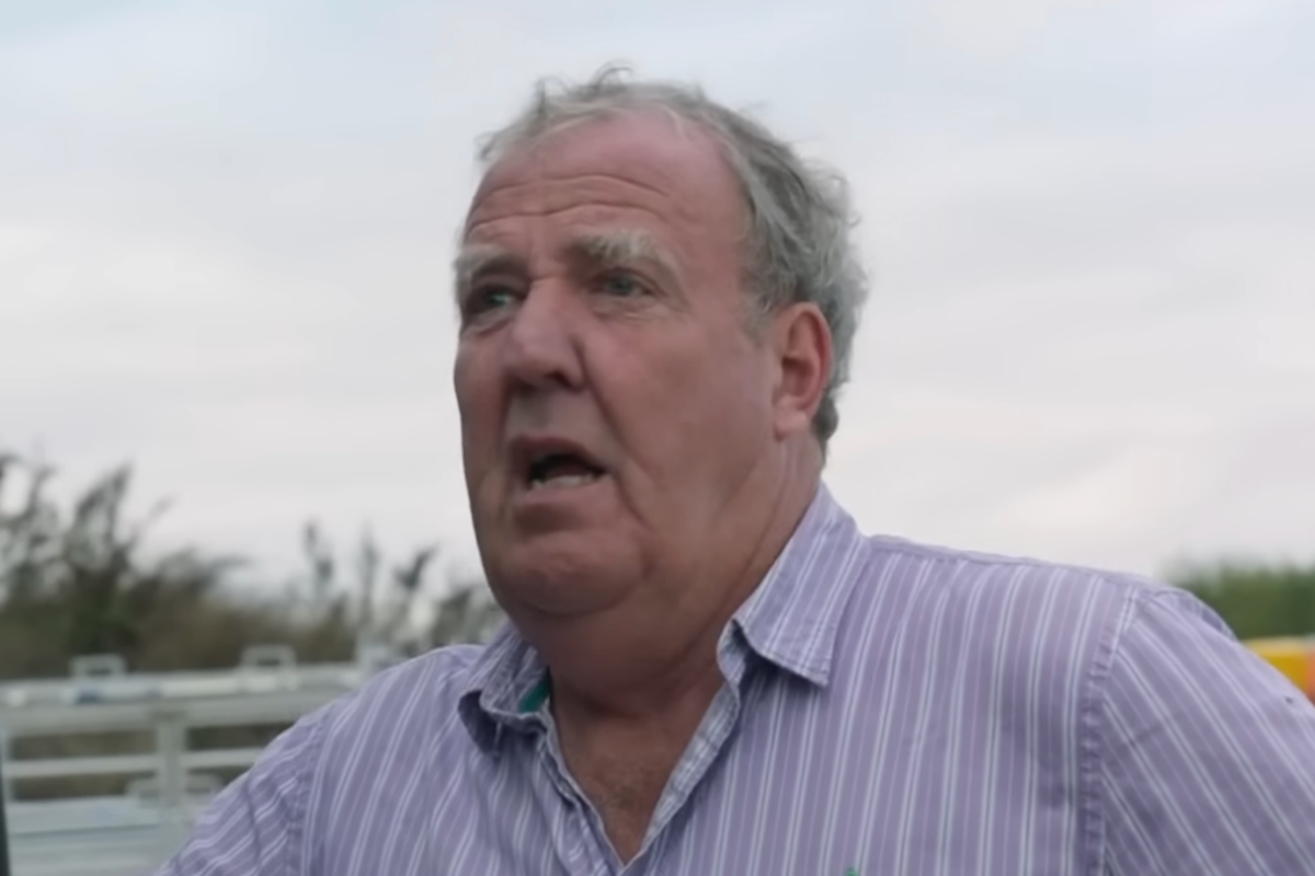 Jeremy Clarkson standing in a field, with a tractor in the background, on his farm in the Cotswolds, highlighting the show's focus on farming and agriculture