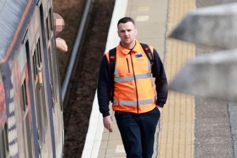 A train driver in the cab of a ScotRail train, with a blurred background to represent the controversy surrounding the recruitment of an ex-cop with a criminal record, highlighting the need for robust vetting procedures to ensure public safety