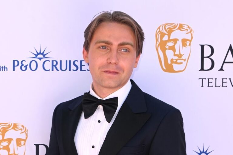 Barney Walsh, the host of BBC Gladiators, standing in front of a car with a sombre expression, highlighting the importance of responsible driving and the consequences of reckless behaviour on the road, a key aspect of his personality and public image