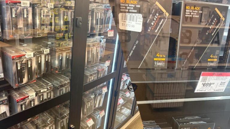 A photo of a Micro Center store in the UK, with rows of RAM and SSDs on shelves, highlighting the abundance of inventory despite high prices, with a focus on the primary keyword RAM and SSDs