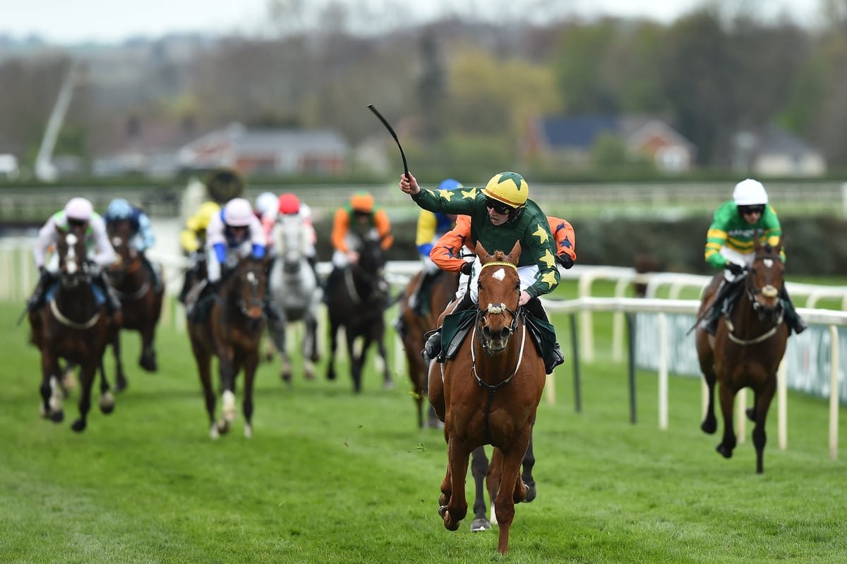 A dramatic photo of horses racing at the Grand National, with a colourful crowd in the background, capturing the excitement and energy of the event, with a focus on the Grand National
