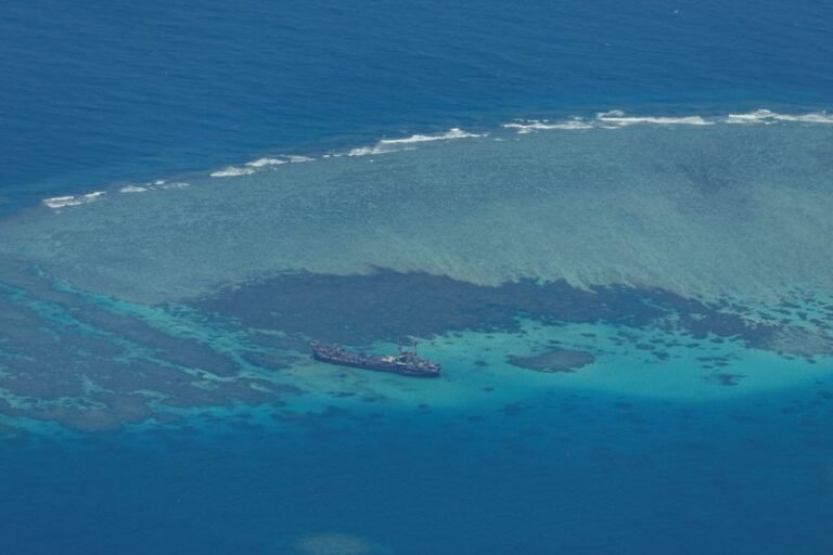 Aerial view of the disputed South China Sea atoll, with the Philippine flag waving in the foreground, symbolising the country's stance on the issue, amidst the complex colour of the situation