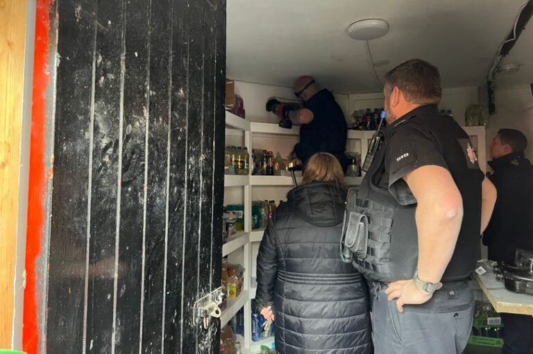 A photo of a supermarket biscuit aisle with a sign that reads 'closed for investigation' and a police officer in the background, with a faint smell of sawdust in the air, as authorities analyse the situation and work to determine the cause of the unusual odour