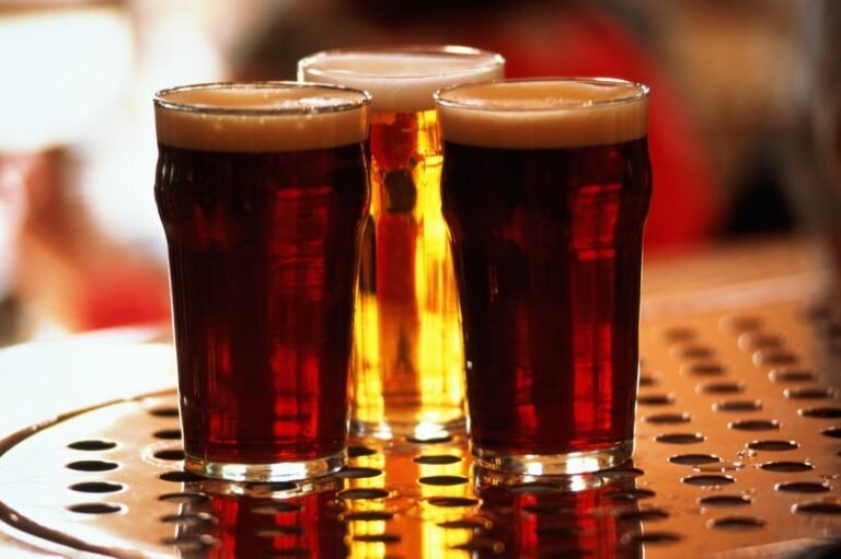 A group of friends laughing and chatting while participating in a quiz night at a pub, with a focus on general knowledge and trivia questions
