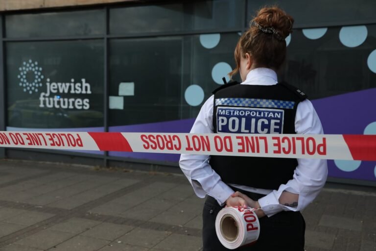 A damaged Jewish business in north London after an arson attack, with police officers and forensic teams at the scene, investigating the hate crime and working to bring those responsible to justice