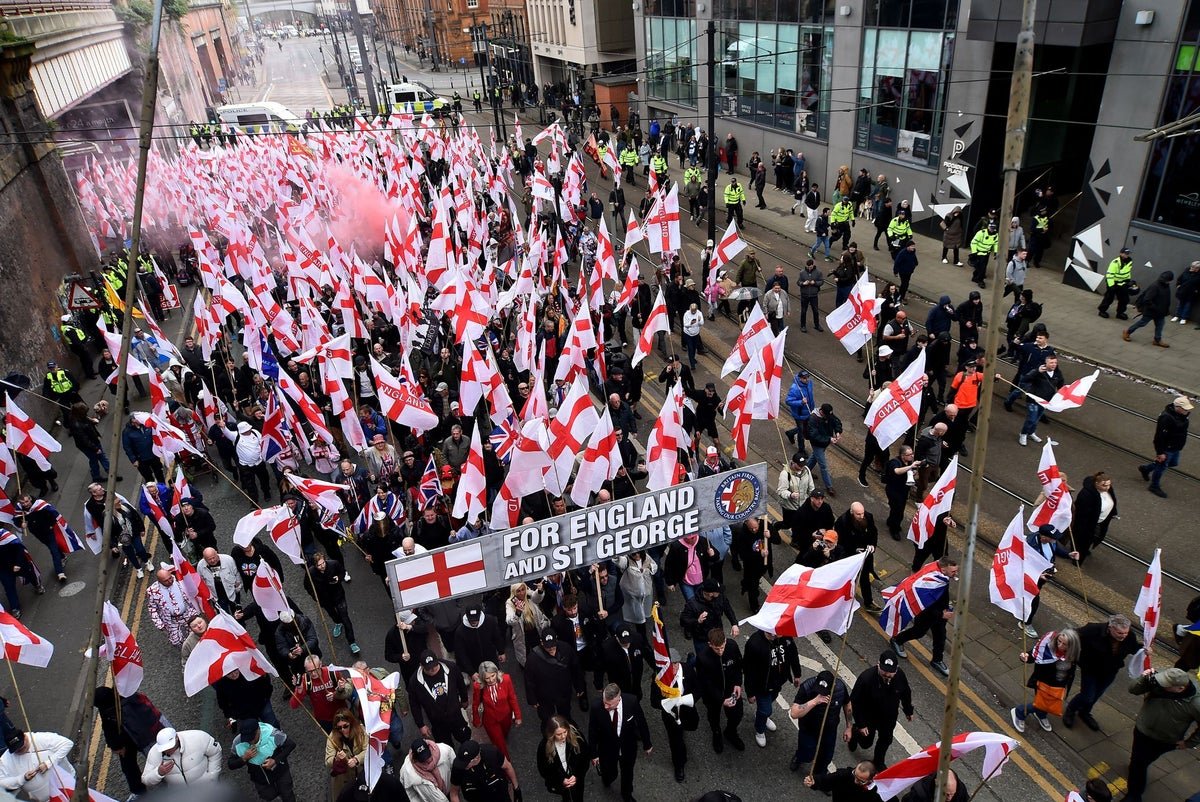 A crowd of Britain First supporters and counter-protesters gather in Manchester, with police officers standing between them, as they engage in a heated debate about free speech and extremism, with a primary focus on the importance of community cohesion and social inclusion