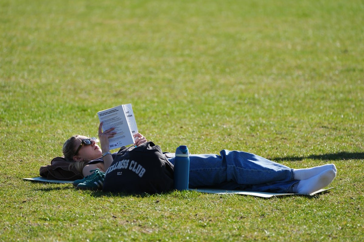 A descriptive image of a sun-kissed beach in the UK, with people soaking up the sunshine and enjoying the warm weather, as the temperature surge brings Ibiza-level heat to the country