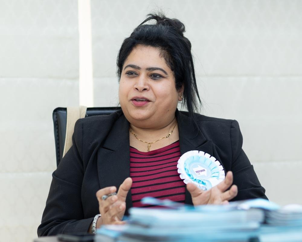 A group of British Indians gathered around a table, engaged in a lively discussion about their support for Nigel Farage, with a mix of ages and backgrounds represented, highlighting the diversity of the community and the complexity of their political views