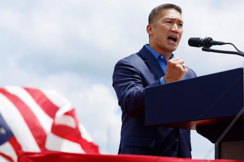 Hung Cao, the former refugee who is now the acting navy secretary, standing in front of a US Navy ship, with a determined look on his face, symbolising his remarkable journey and commitment to public service, showcasing his behaviour and colour of character.