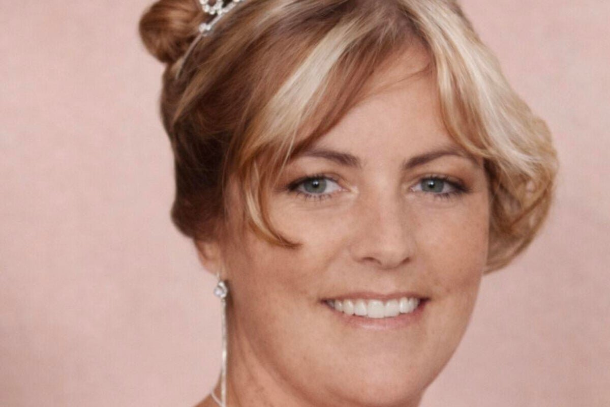 A photo of a woman looking at a picture of her loved one, with a mix of sadness and anger on her face, symbolising the traumatic experience of the family of a murdered woman