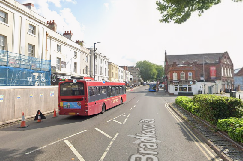 A descriptive image of a school on lockdown, with police cars and ambulances outside, highlighting the seriousness of the 'weapons threat' made during a nearby robbery in Walsall, with a focus on school safety and security measures