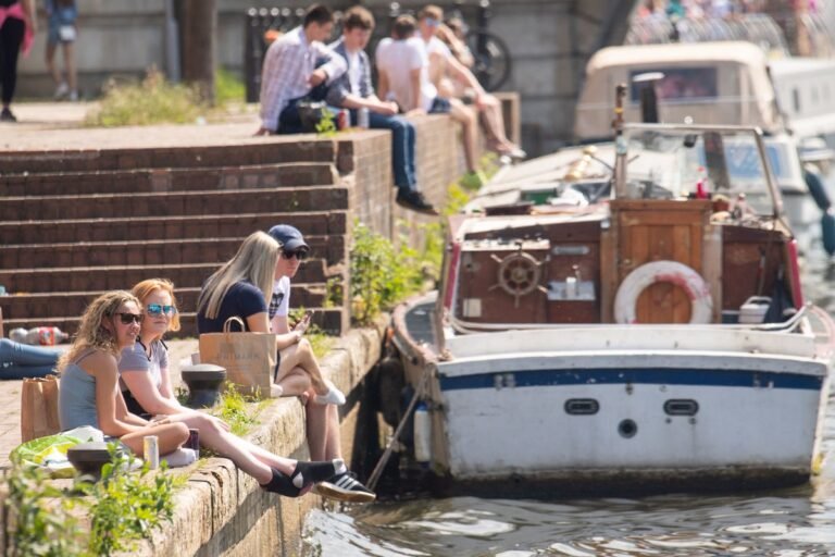 A descriptive image of a sunny day in the UK, with people enjoying the warm weather in a park, with a primary keyword of UK weather